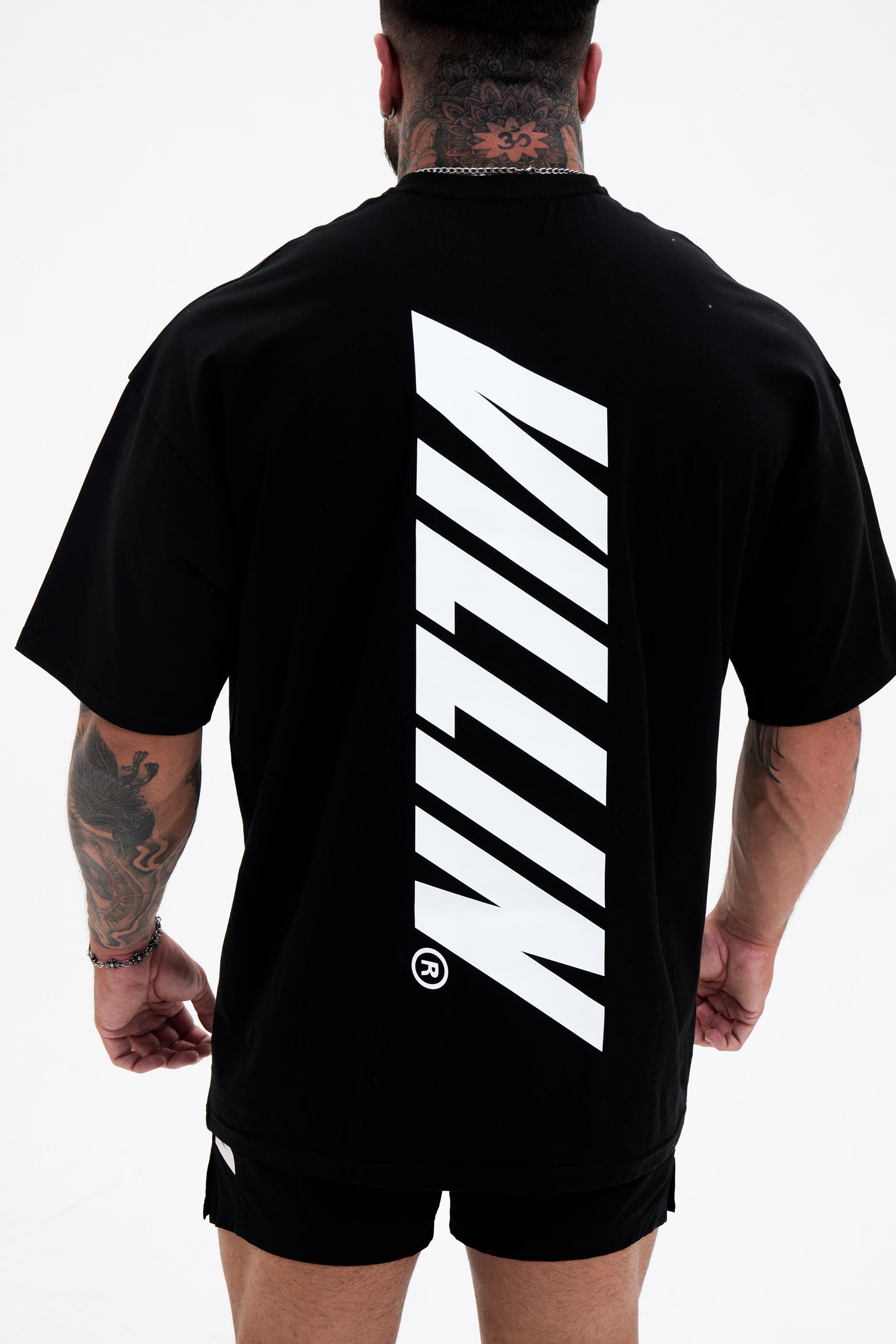 Person wearing a black t-shirt with a white VILLAIN logo on the back against a white background