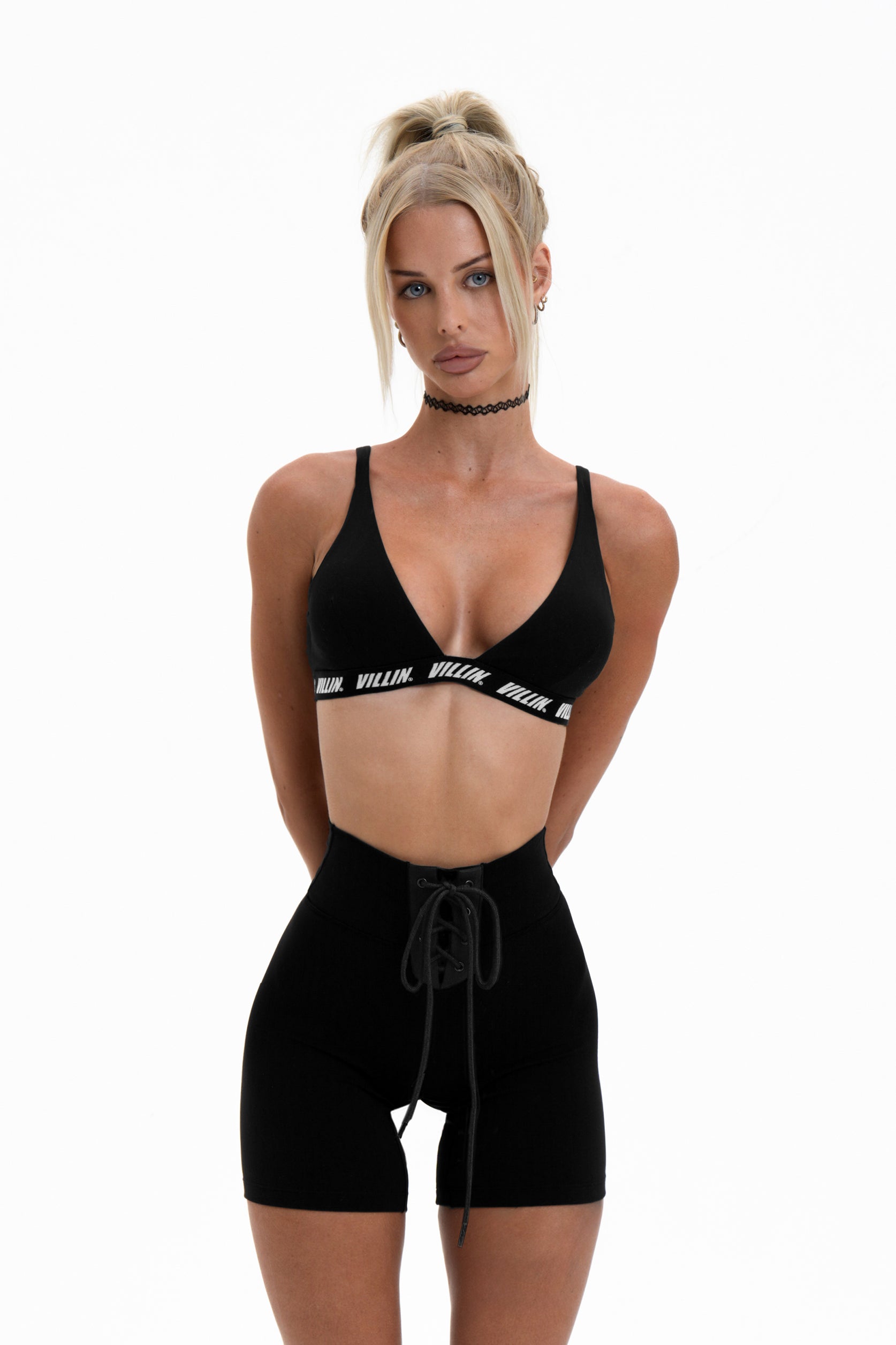 Woman wearing a black sports bra and shorts with visible branding on a white background